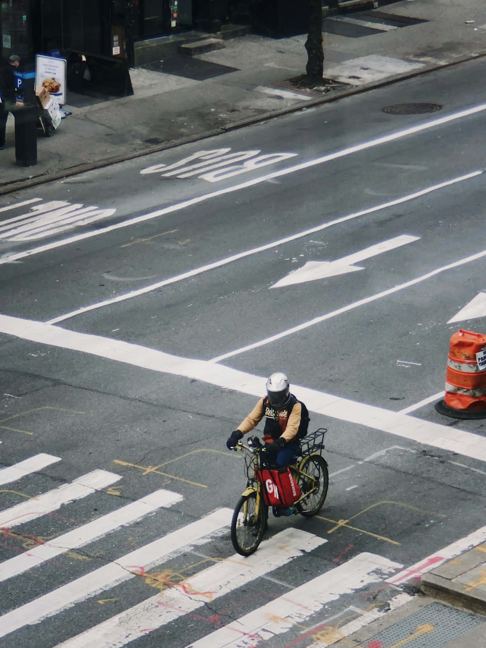 homem na jaqueta preta que anda de bicicleta na faixa de pedestres durante o dia