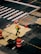 A person wearing a bright safety vest and helmet walks across a construction zone in an urban area. Orange traffic cones and barriers are placed around a section of the road, which appears to be under repair. The street is marked with white lines and other construction-related markings.