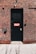 A black door with a red and white 'FACP' sign is set into a brick wall. The wall features a combination of brown and red bricks with contrasting white mortar. Above the door are two security cameras, and near the door handle, there is a small caution sign.