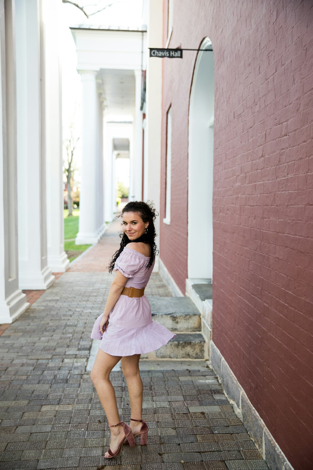 girl in pink dress standing beside brown brick wall during daytime