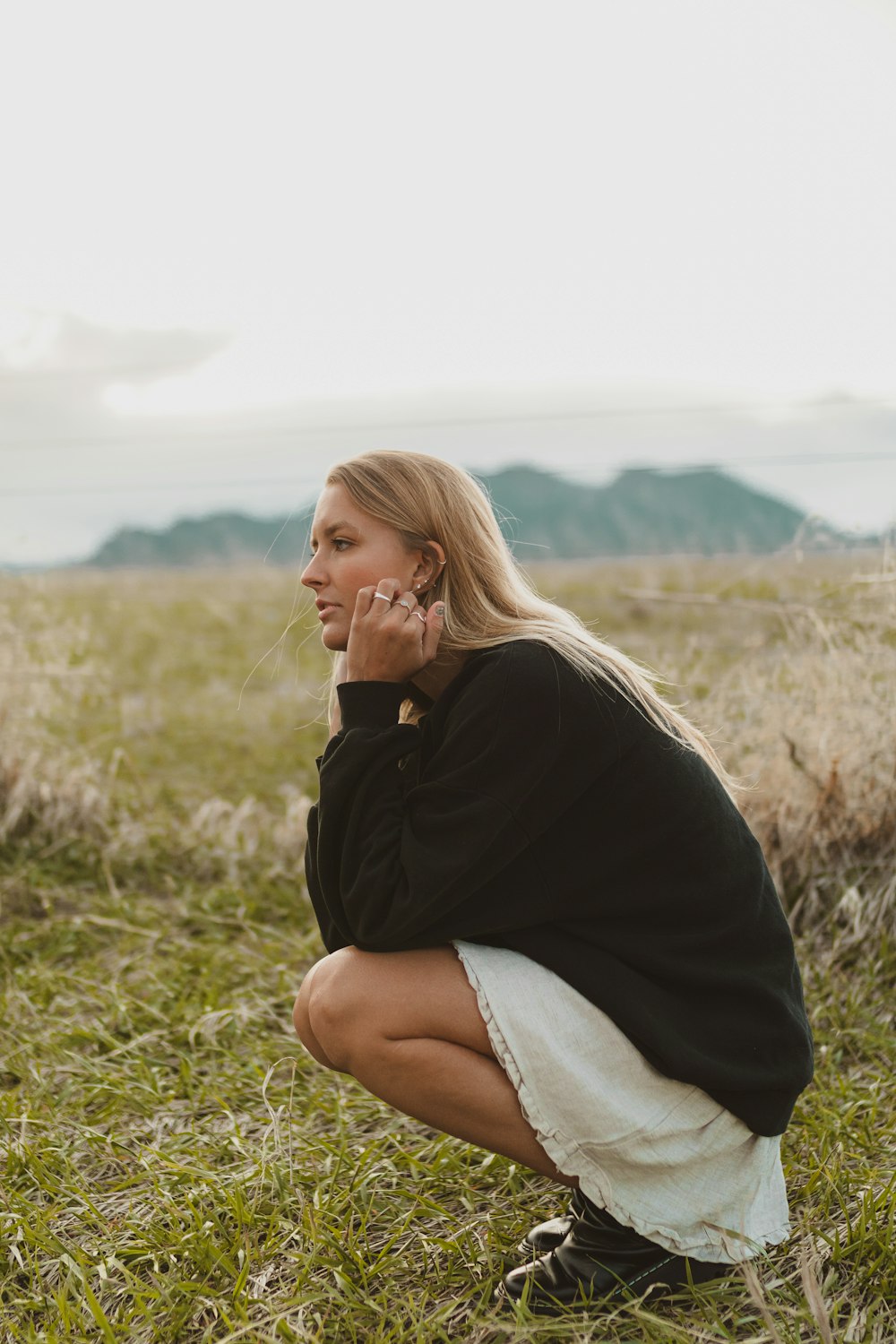 woman in black long sleeve shirt and gray denim shorts sitting on green grass field during