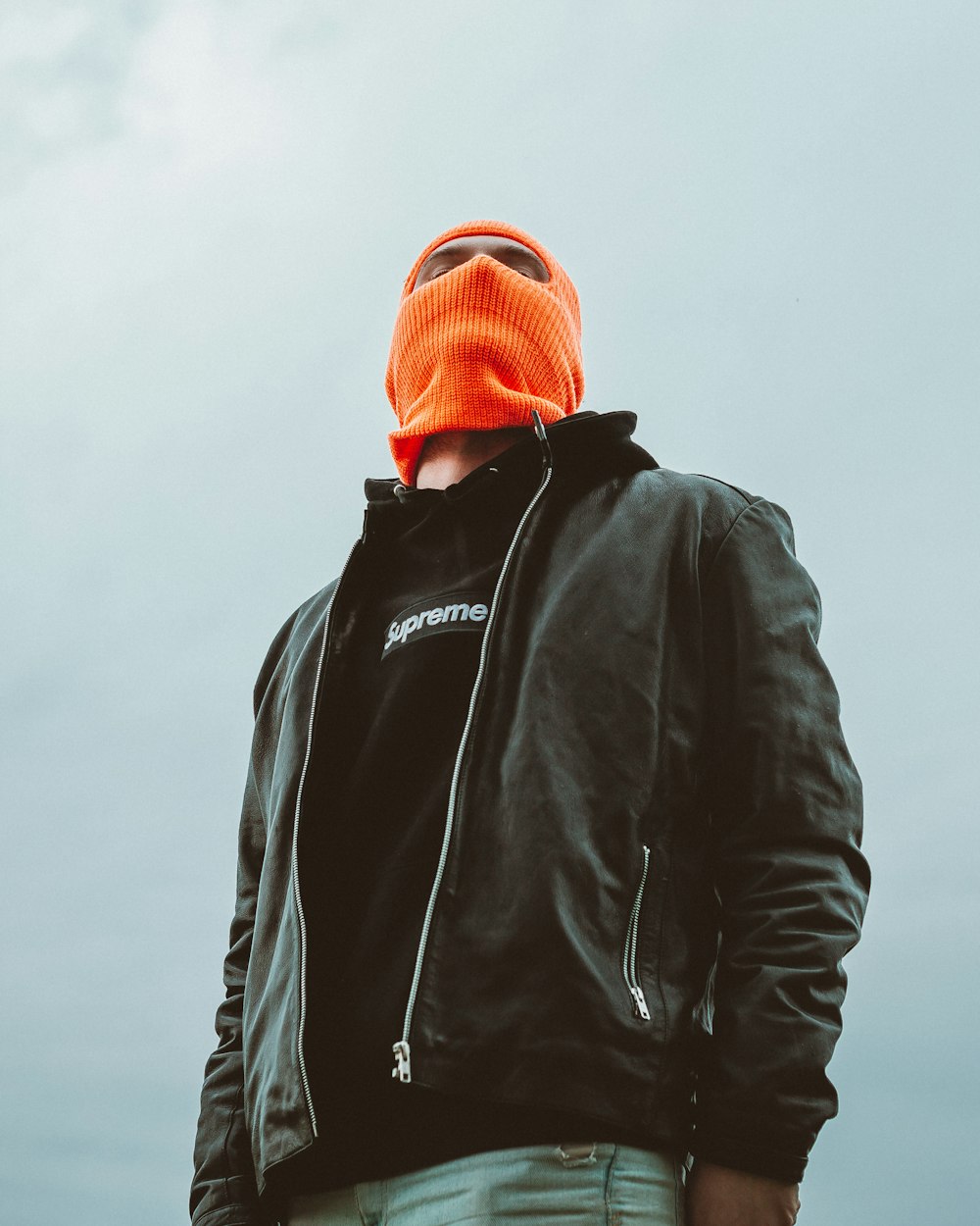 uomo in giacca nera e berretto in maglia arancione