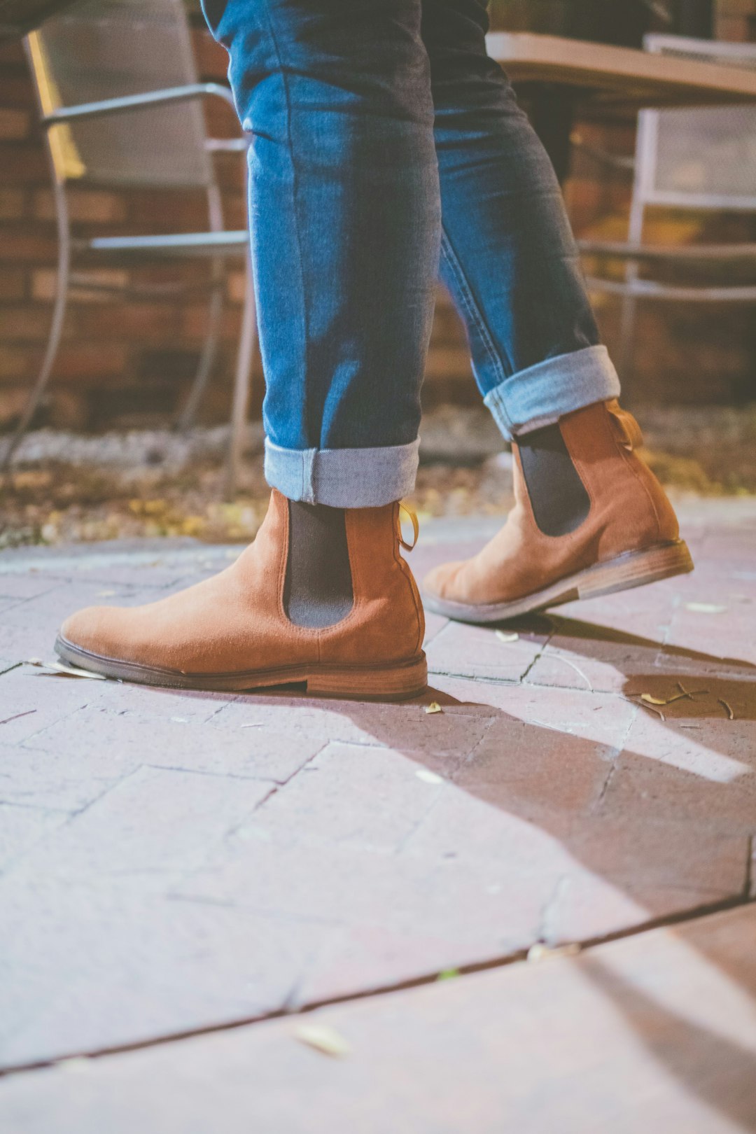 person in blue denim jeans and brown leather boots