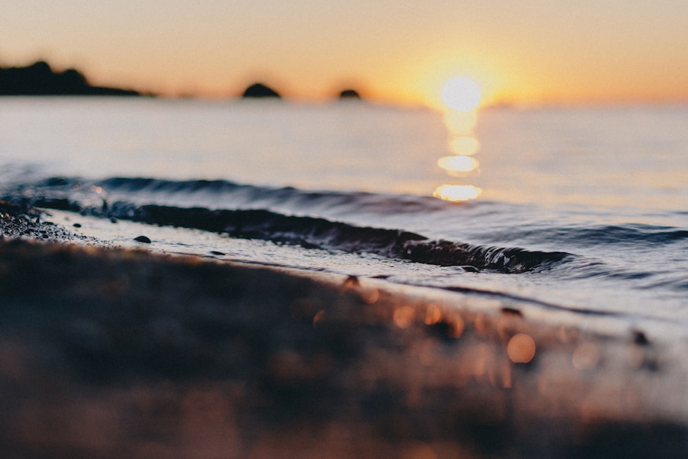 water waves on shore during sunset