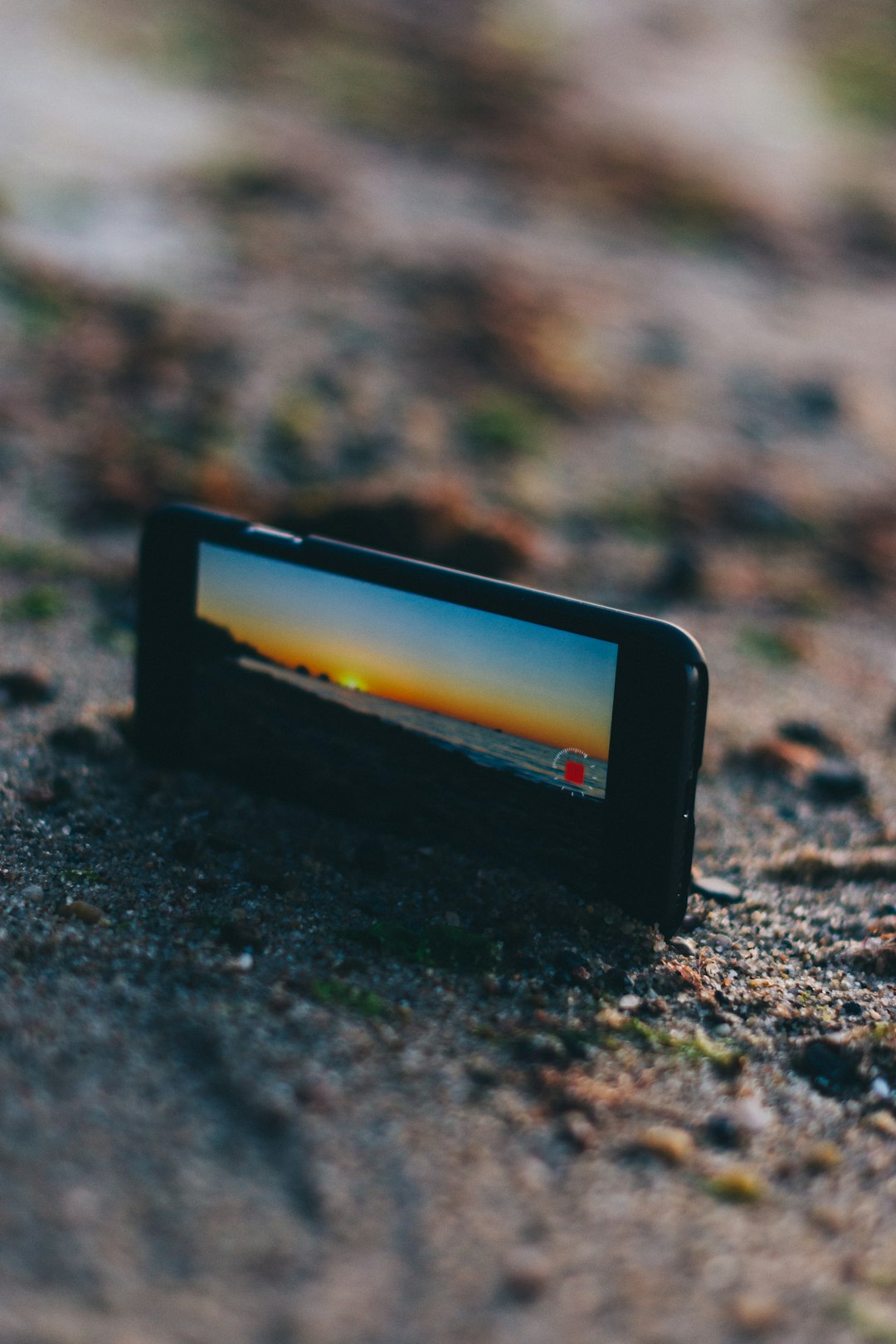 black smartphone on brown sand