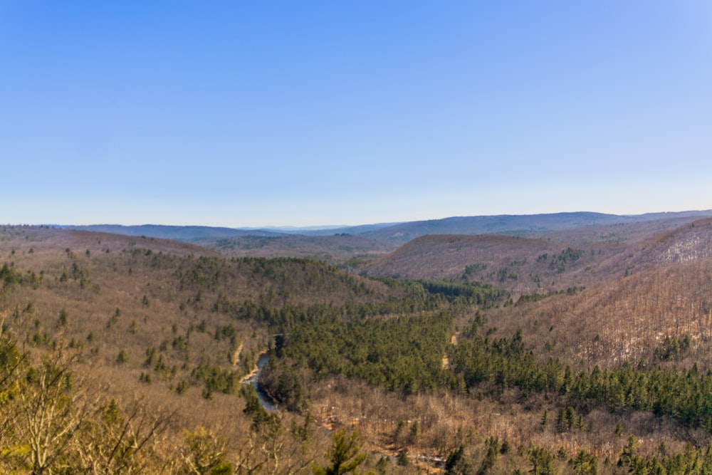 green grass field near brown mountain under blue sky during daytime