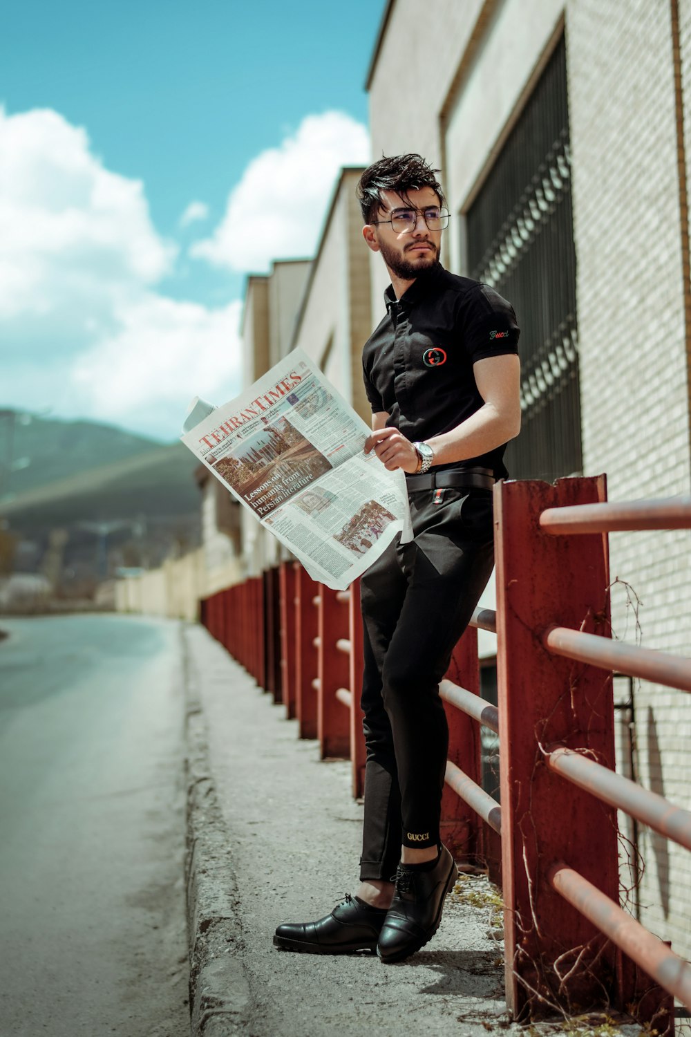 Mann im schwarzen Poloshirt hält Zeitung in der Hand