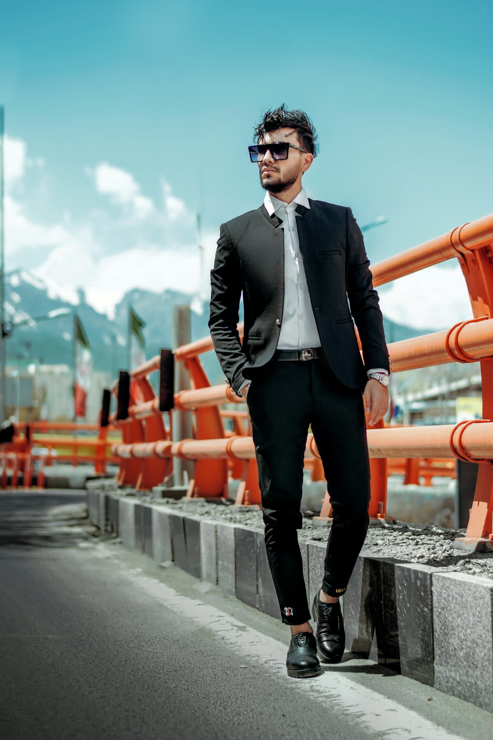 man in black suit standing on gray concrete road during daytime