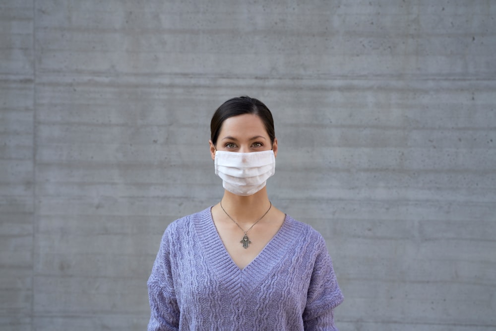 woman in blue v neck sweater wearing white face mask