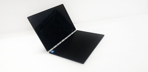 A sleek, black laptop with a flexible hinge is partially open, displaying its screen and keyboard against a white background.