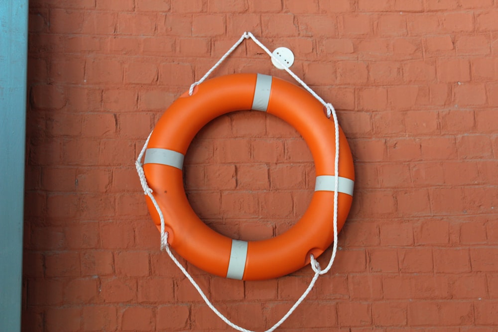 orange and white life buoy on brown brick wall