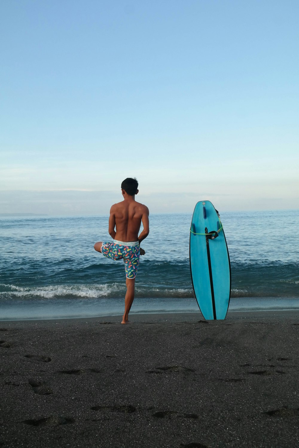 man in blue and white shorts holding blue surfboard walking on beach during daytime