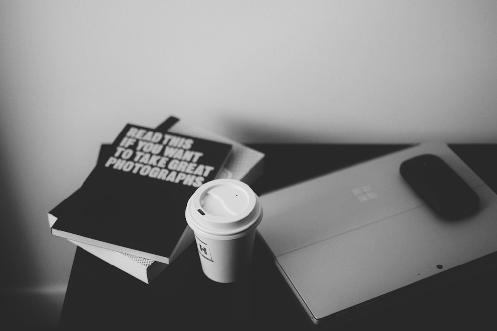 macbook pro beside white ceramic mug on table