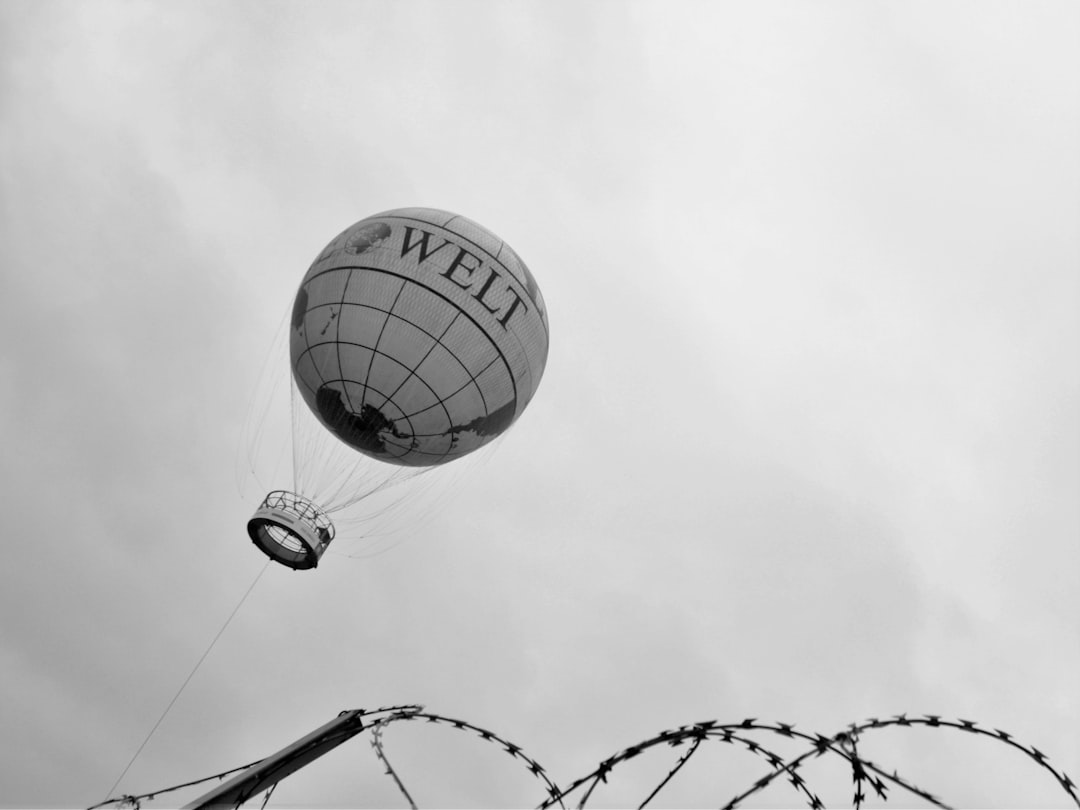 grayscale photo of hot air balloons on wire fence