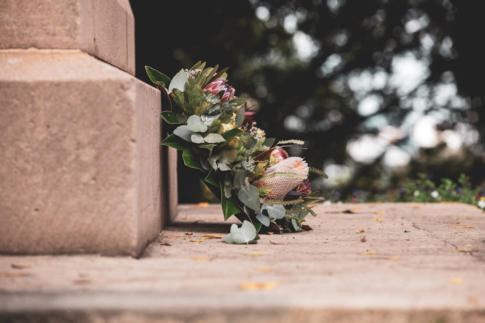 pink and green flower bouquet on brown concrete wall