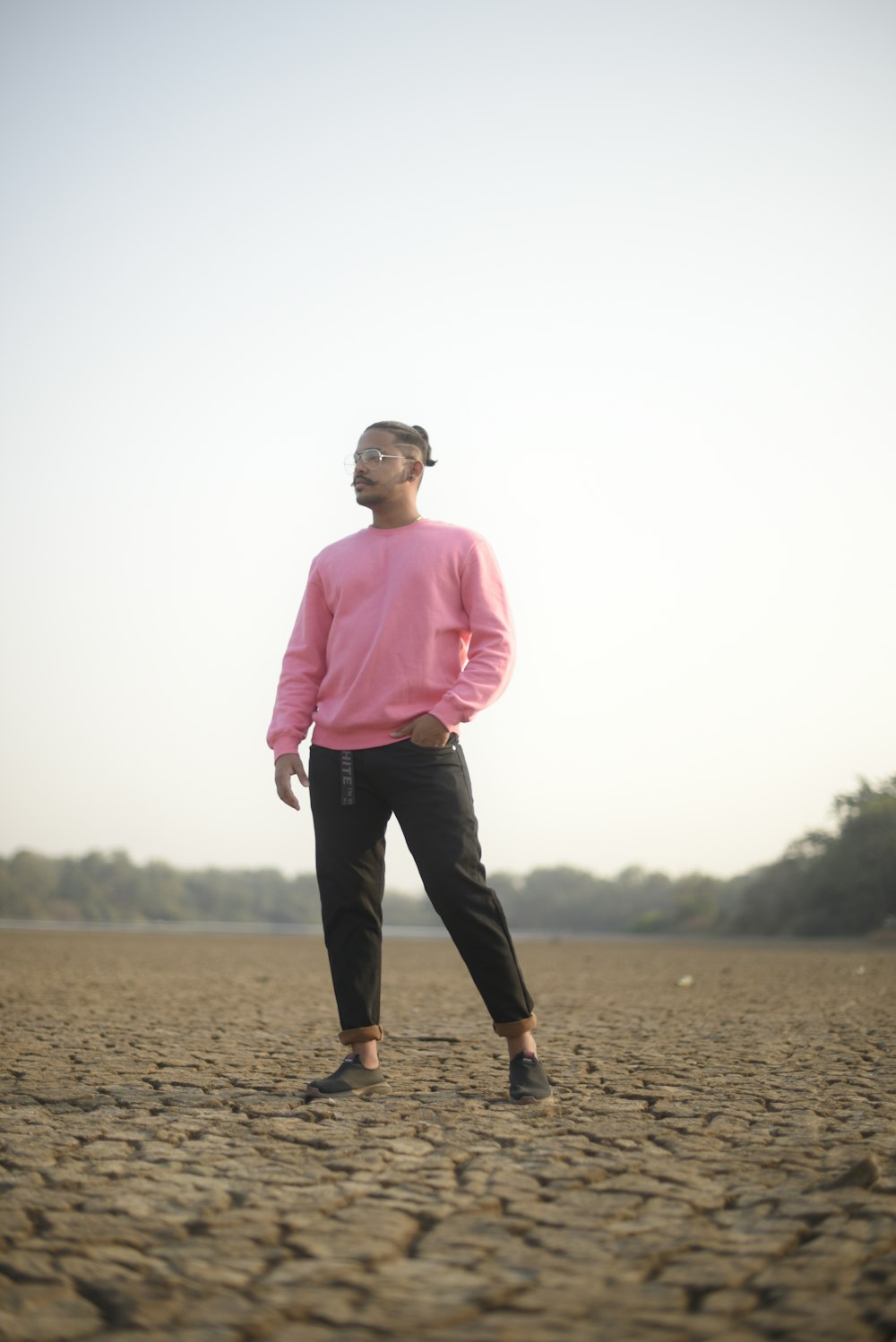 man in pink dress shirt and black pants standing on brown sand during daytime