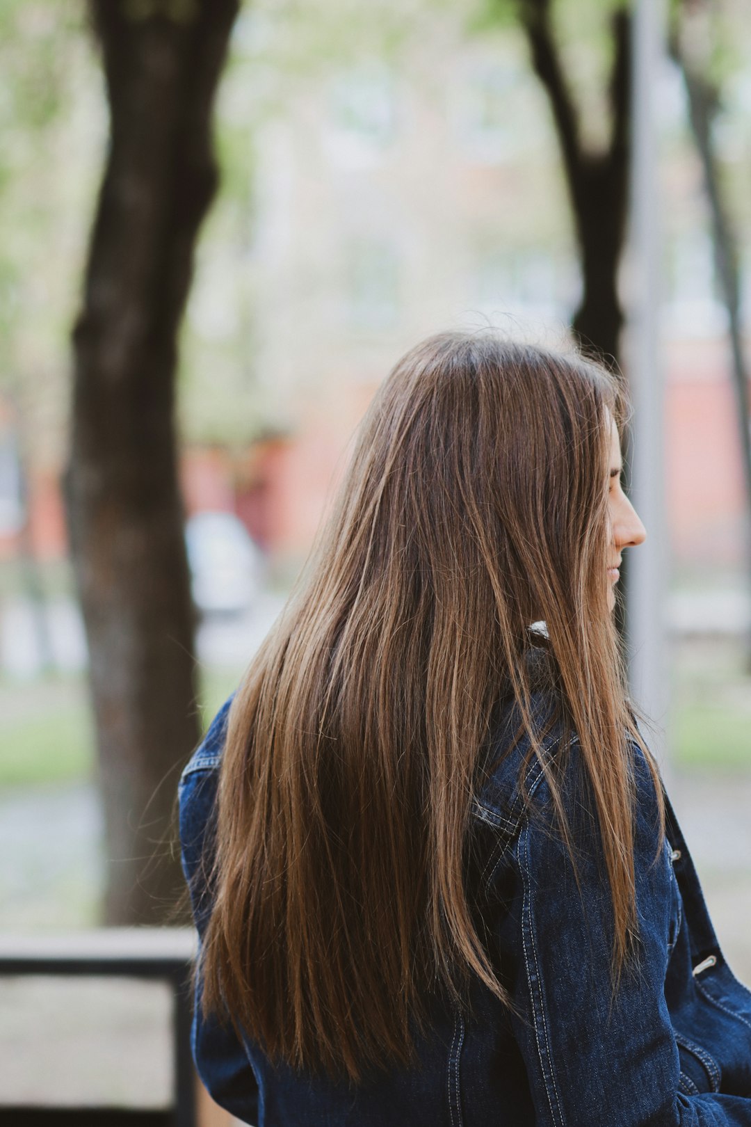 woman in blue denim jacket standing near trees during daytime