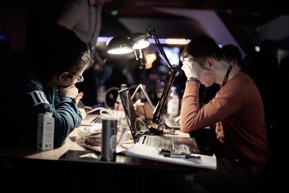 man in red long sleeve shirt sitting in front of table with laptop computer