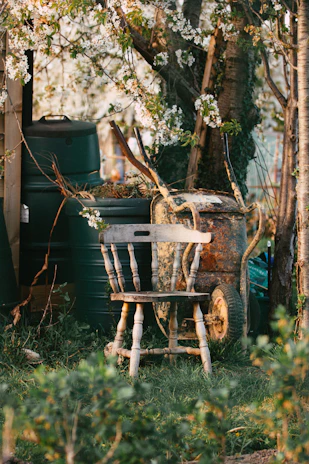 A hand-crafted wooden chair resting beside a blooming garden bed.