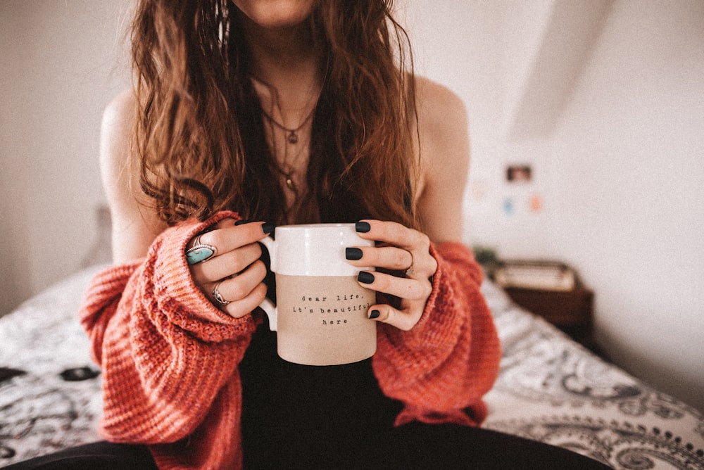 woman in black tank top holding white ceramic mug