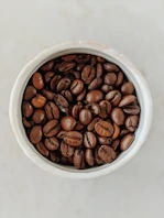 brown coffee beans in white ceramic bowl