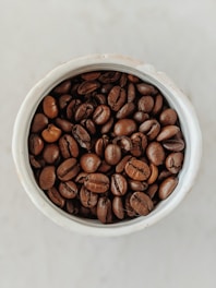 brown coffee beans in white ceramic bowl