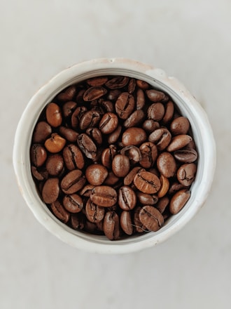 brown coffee beans in white ceramic bowl