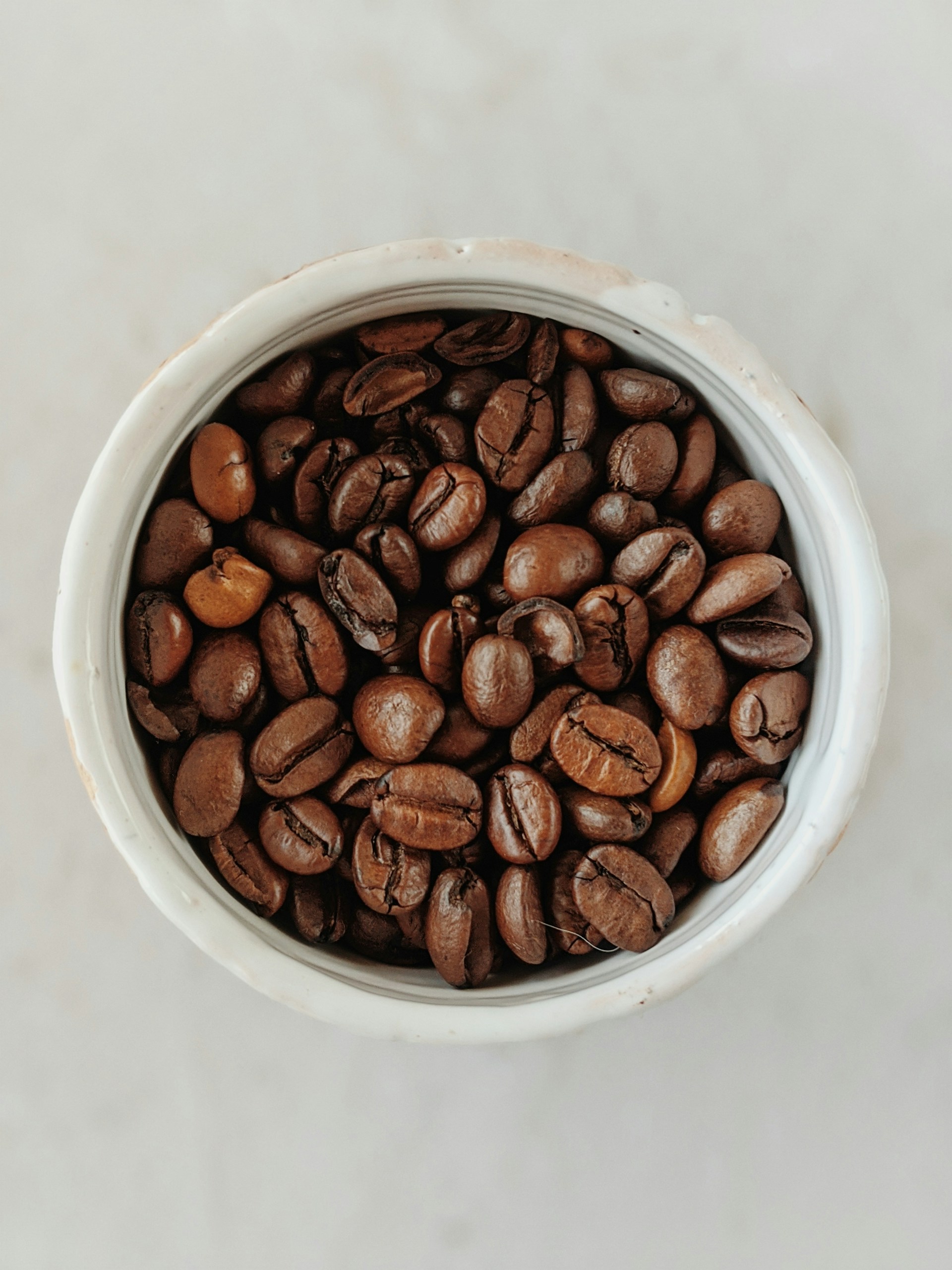 brown coffee beans in white ceramic bowl