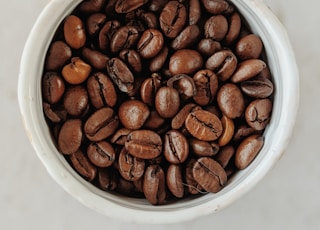 brown coffee beans in white ceramic bowl