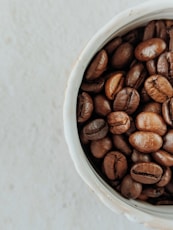 brown coffee beans on white ceramic bowl