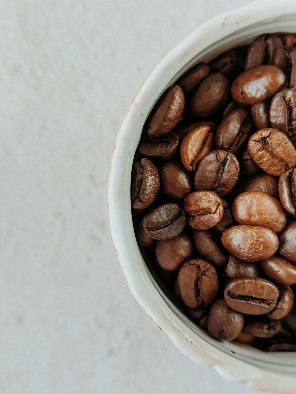 grains de café bruns sur bol en céramique blanche