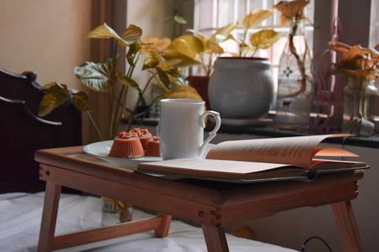 white ceramic mug on white book page on brown wooden table