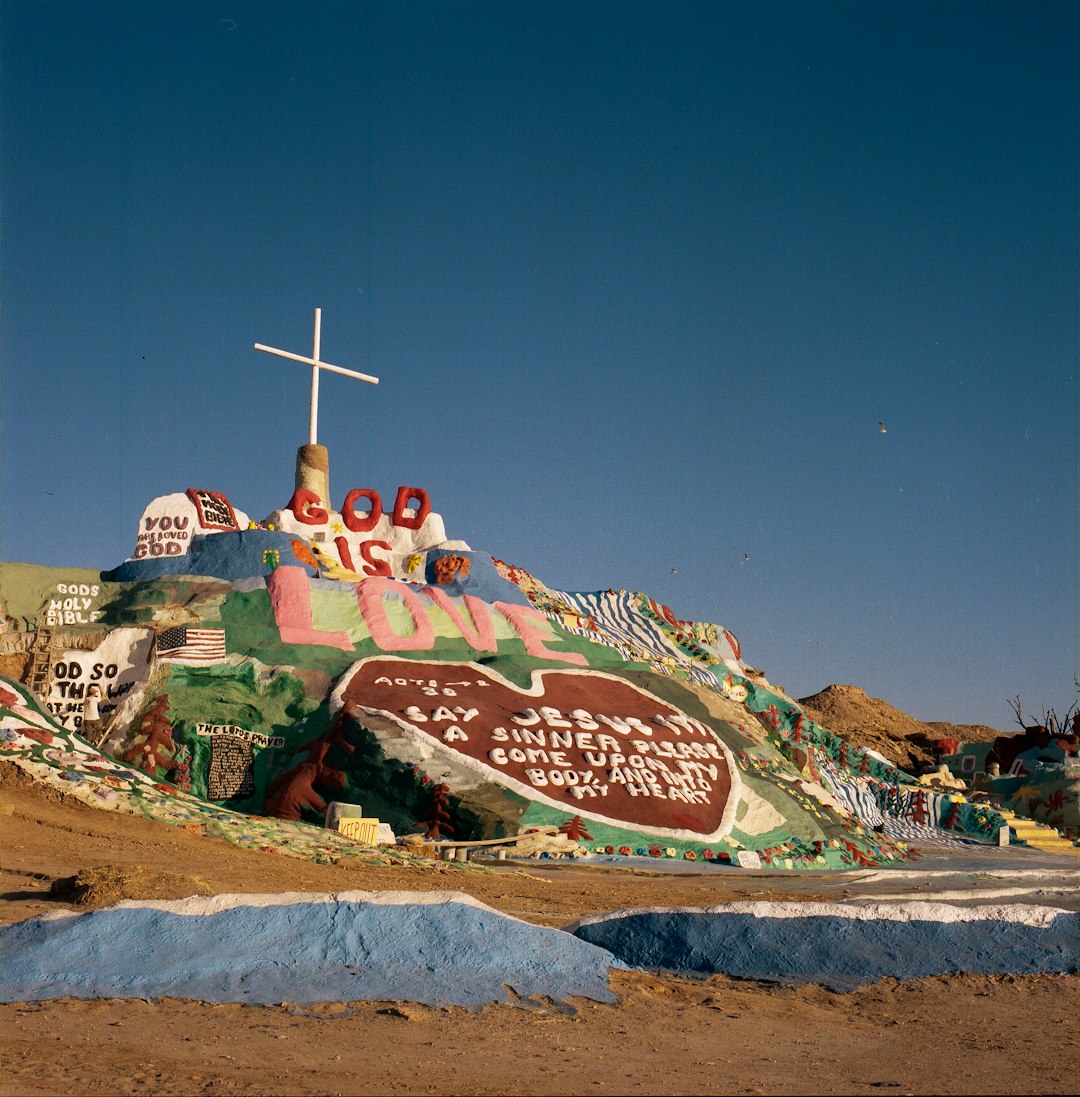 red and yellow graffiti on brown sand during daytime