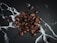 A collection of roasted coffee beans scattered on a dark, textured surface with white, marble-like veins running through it.