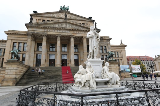 brown concrete building with statue of man and woman in Konzerthaus Berlin Germany
