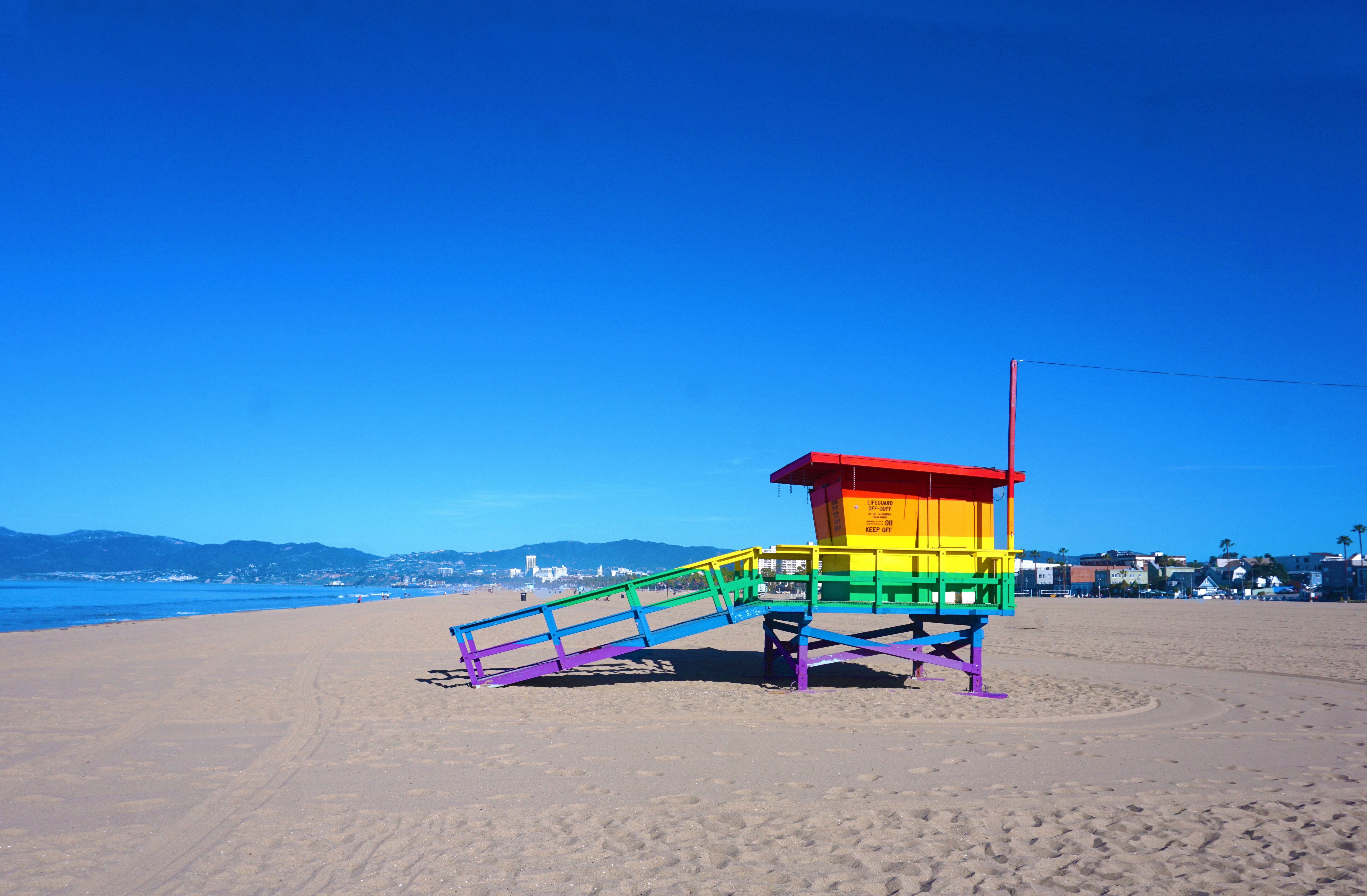 red and blue wooden lifeguard house on beach shore during daytime