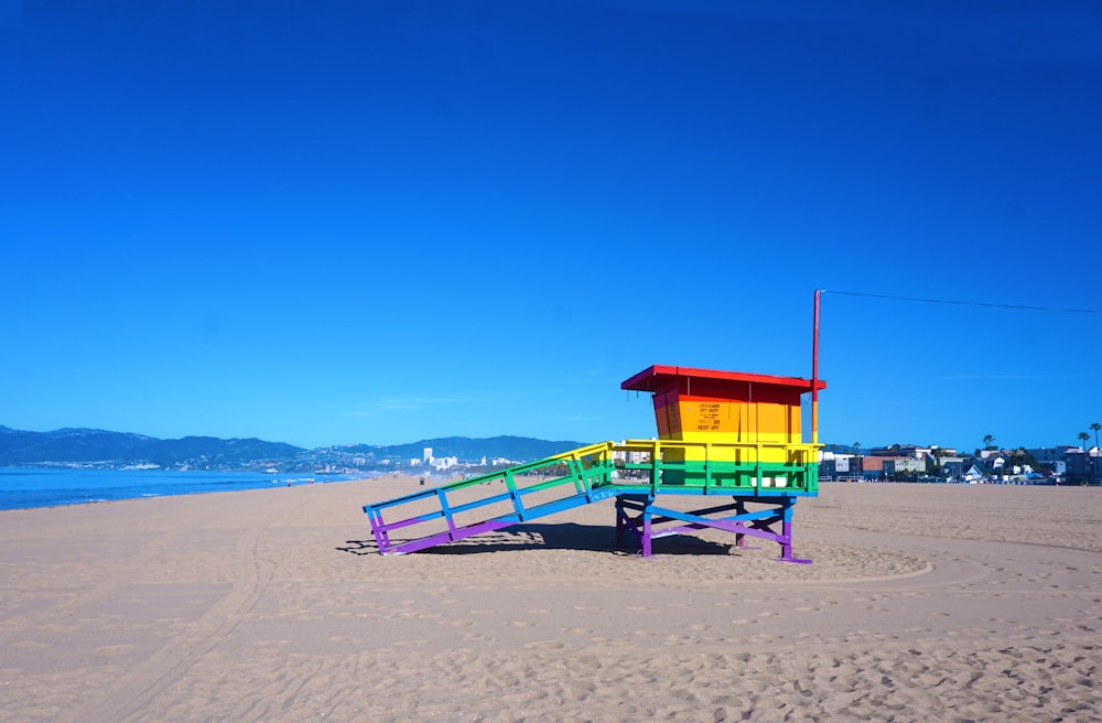 red and blue wooden lifeguard house on beach shore during daytime