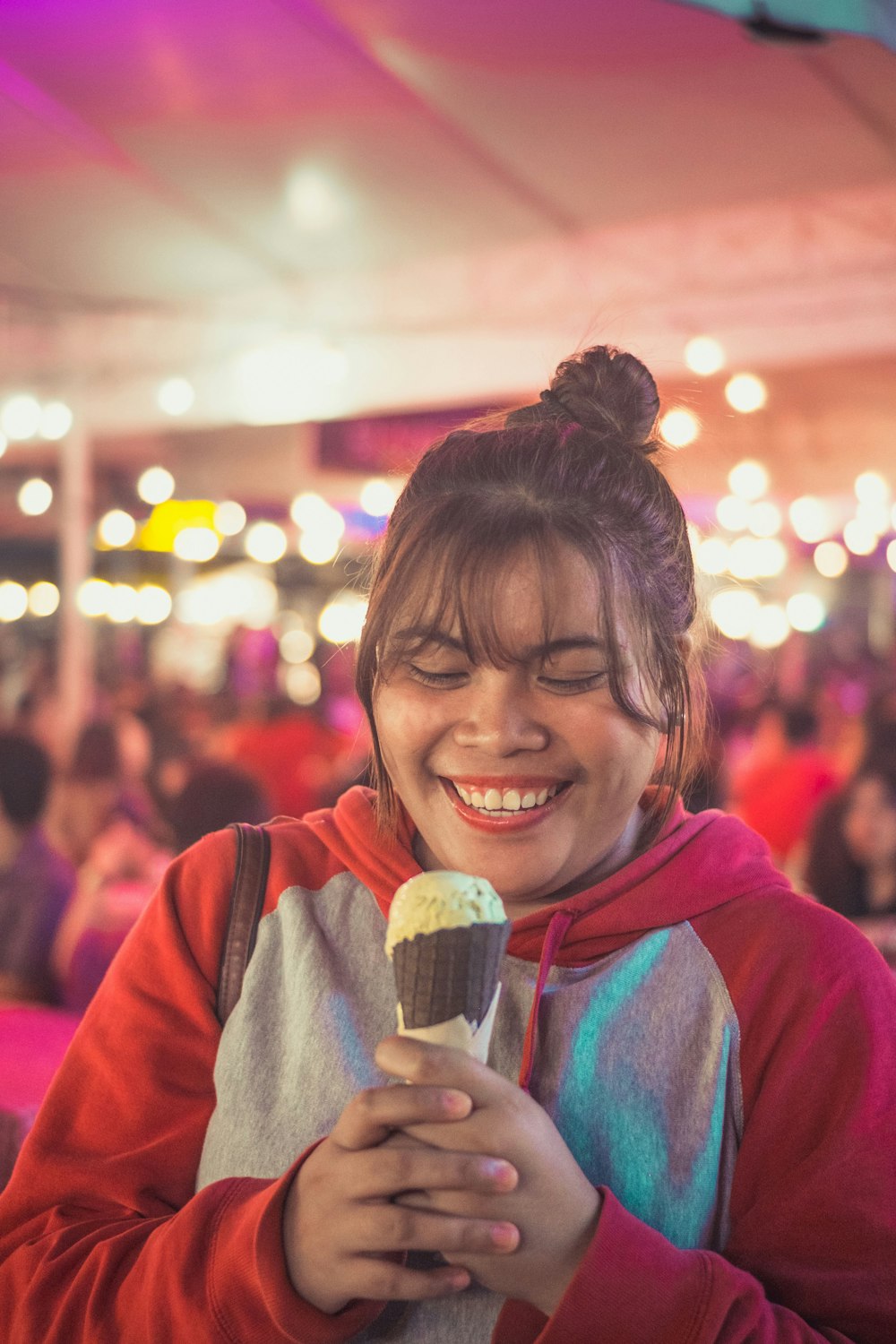 smiling woman in red hoodie holding ice cream cone