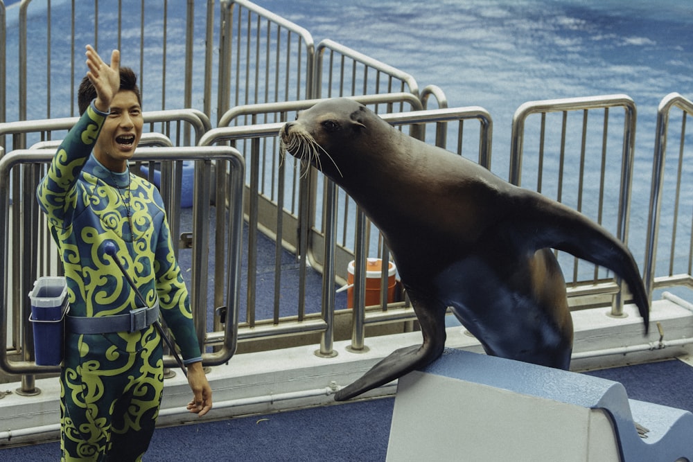 boy in blue and green pajama set standing beside sea lion