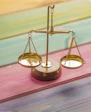 small gold balance scale on colorful wood