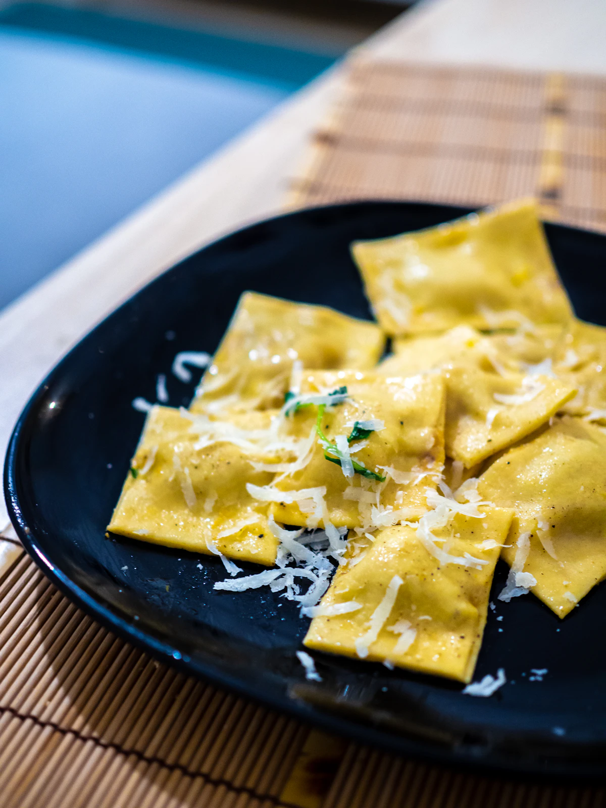 Square cheese ravioli with herbs on a dark plate