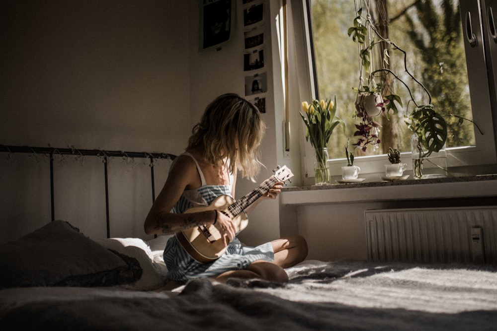 Frau im weißen Tanktop spielt akustische Gitarre