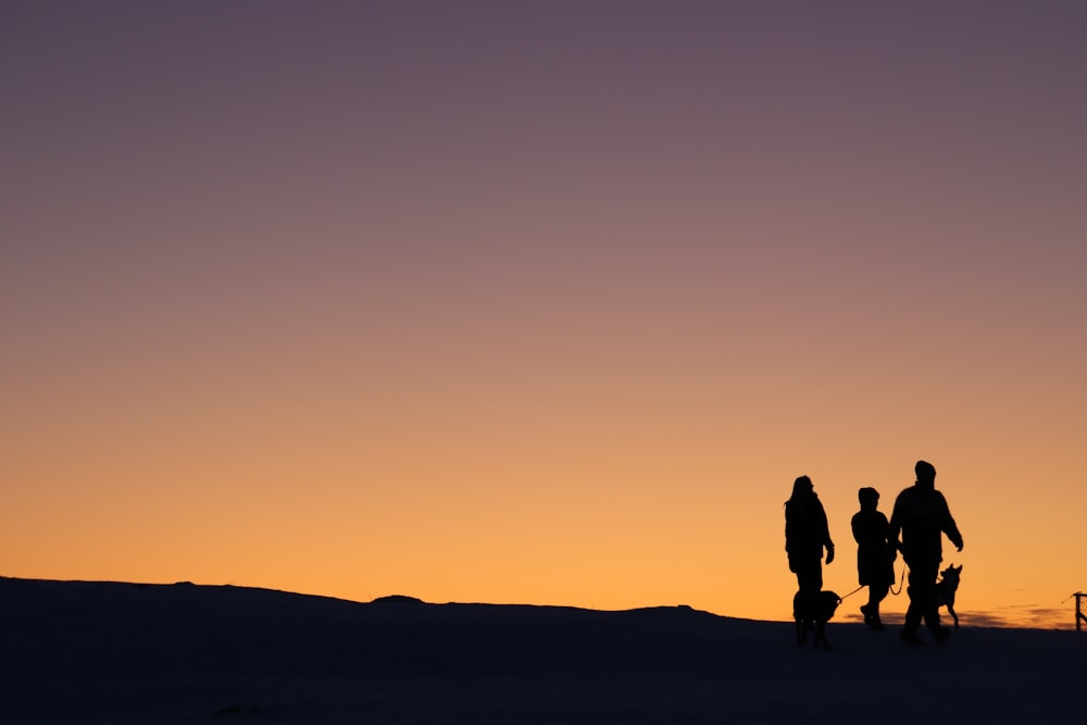 Silhouette von 2 Personen, die während des Sonnenuntergangs am Strand spazieren gehen