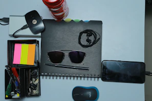 A close-up of a sleek, simple desktop organizer with pens, notes, and a phone charger.