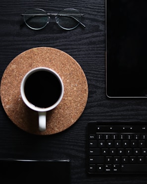 A flat lay of trading tools including charts, a laptop, and coffee.