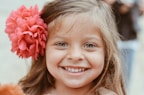 A smiling young girl wearing bright floral hair clips in her hair