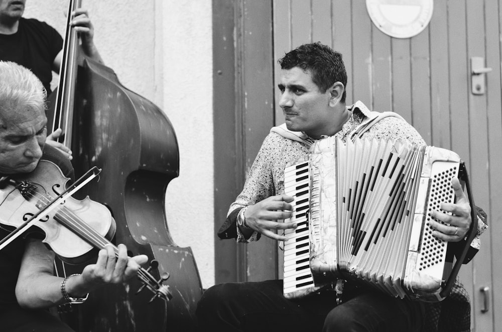 man playing piano in grayscale photography