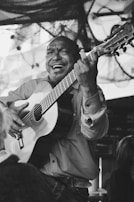 A joyful musician strumming an acoustic guitar outdoors during golden hour.