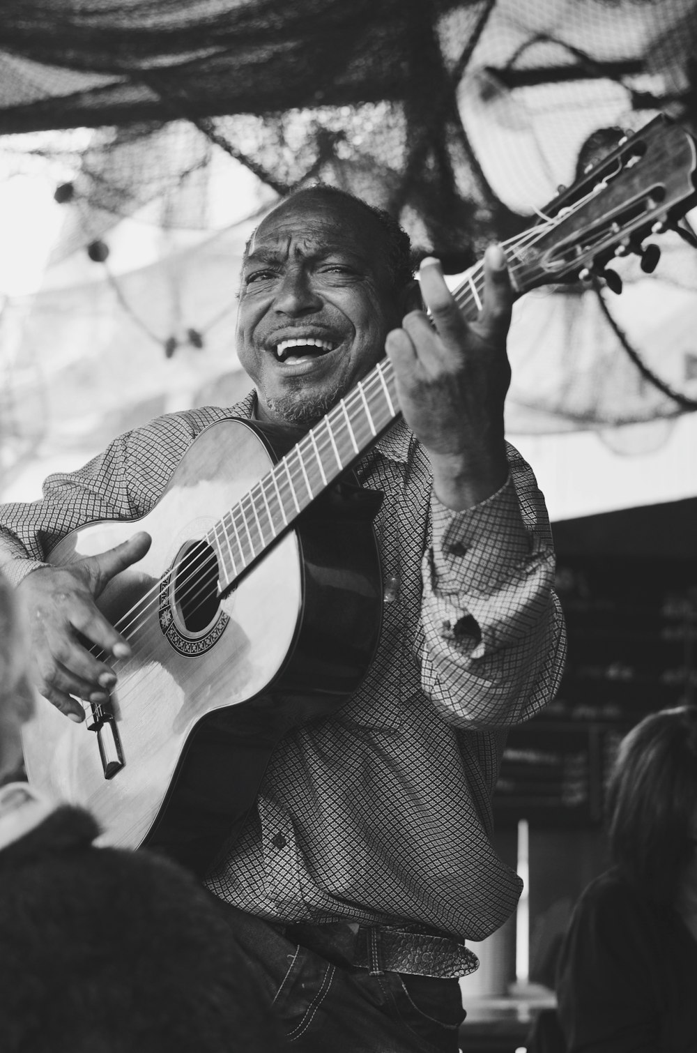 man playing acoustic guitar in grayscale photography