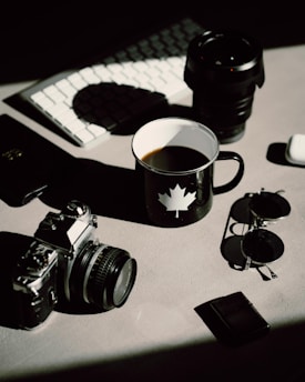 black dslr camera beside black ceramic mug on table